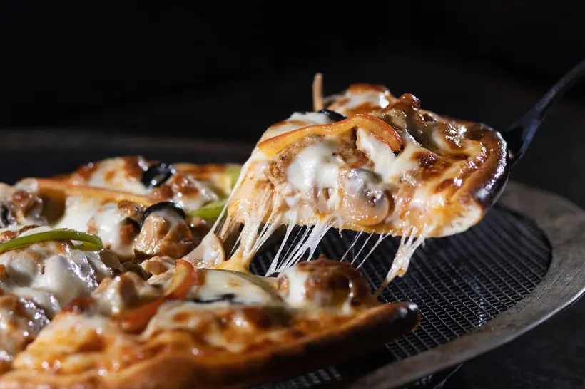 A cheesy pizza slice being lifted